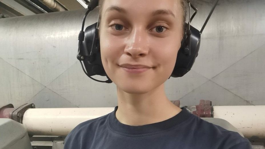 Maskinpersonalen Amanda nere i ett maskinrum med hörselkåpor.