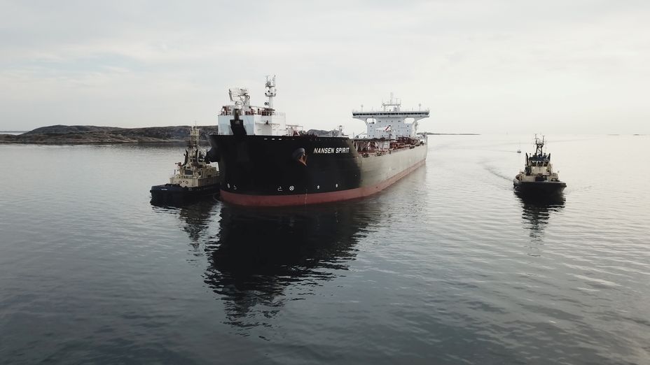 Två bogserbåtar på varsin sida om ett tankfartyg