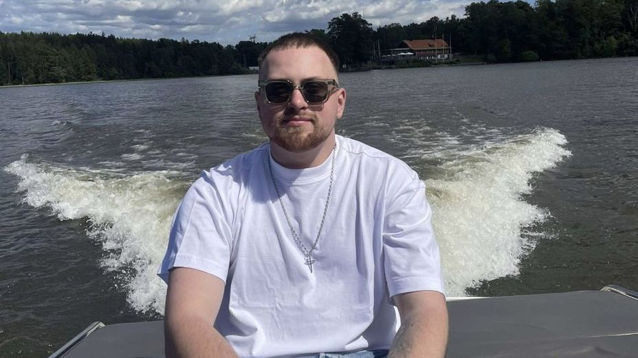Studenten Fredrik sitter i aktern på en fritidsbåten mot en bakgrund av hav och himmel.