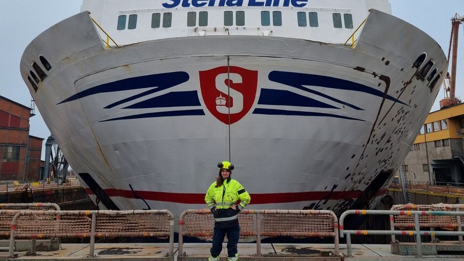 Bild på studenten Karin framför fören på ett av Stena Lines fartyg, klädd i varselkläder och hjälm