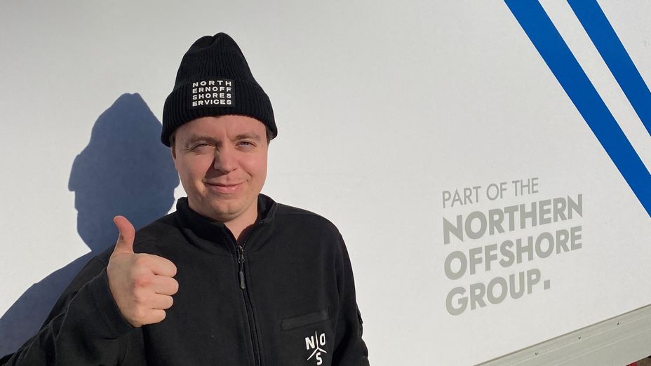 Matrosen Peter står framför ett servicefartyg och ger tummen upp mot kameran.