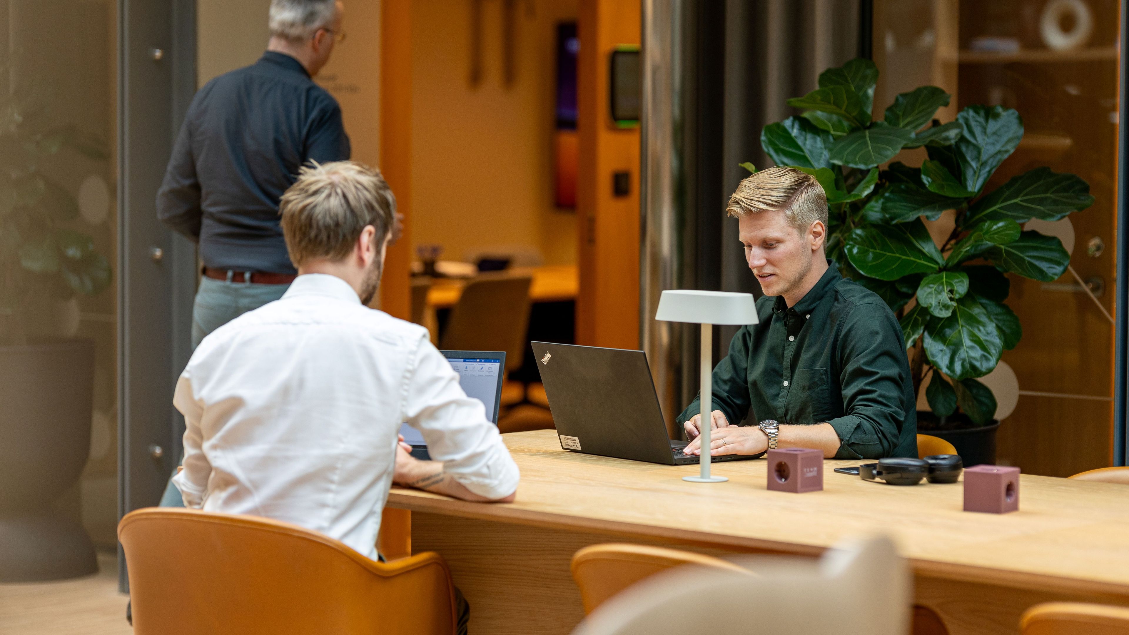 Två kollegor arbetar vid ett bord med varsin laptop.