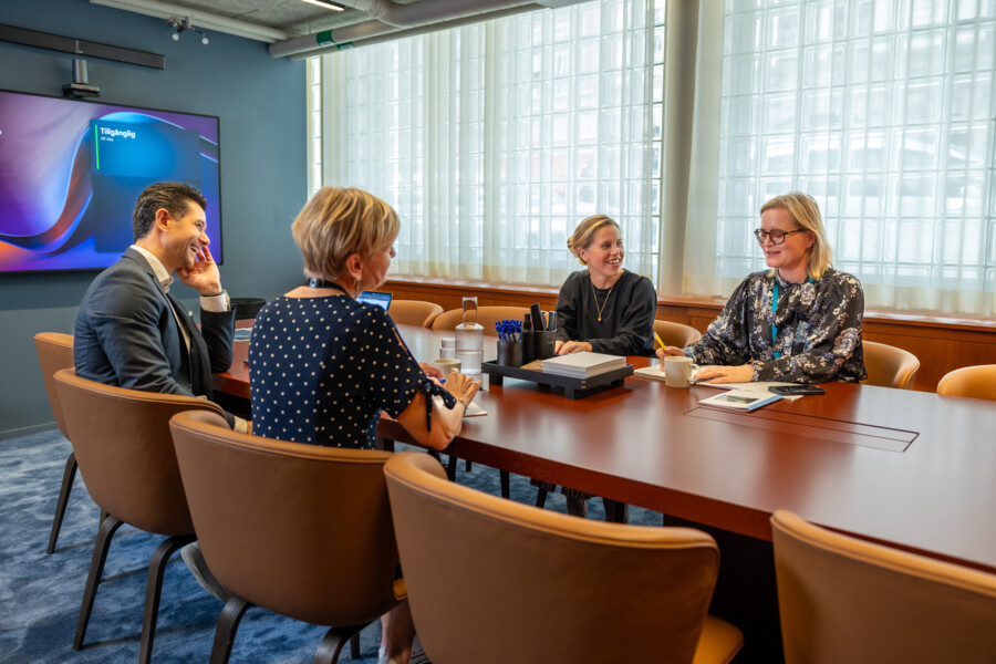 Fyra medarbetare sitter vid ett konferensbord och har ett möte.